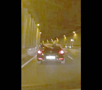 En film på YouTube visar en halvnaken man som åker på taket till en bil genom San Pedro-tunneln.