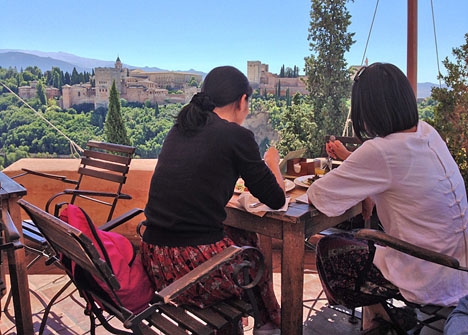 Två turister njuter av en lunch i Granada med Alhambra som utsikt.