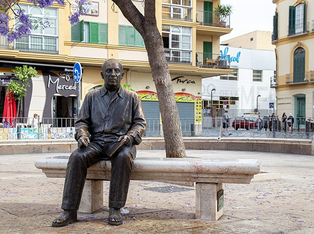 Pablo Picasso sitter staty vid Plaza de la Merced i Málaga, intill sitt födelsehem (till höger) som också är ett museum.