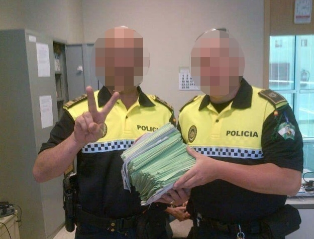 Fotot på två lokalpoliser i Sevilla som ståtar med en hög böter väcker ont blod.